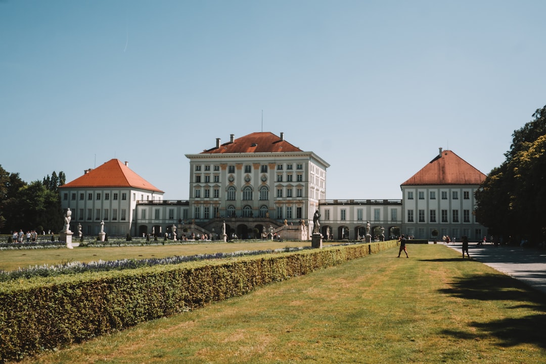 A large white building sitting next to a lush green field