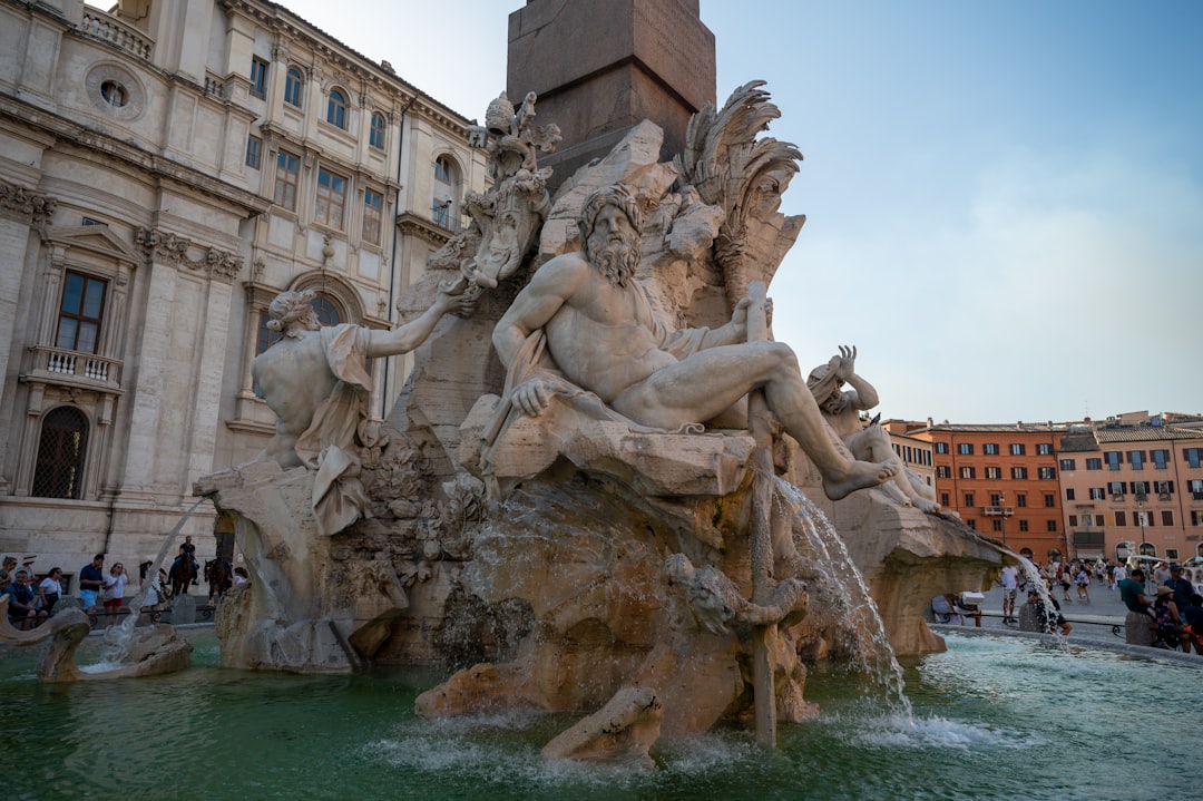 a fountain with statues in front of a building with people