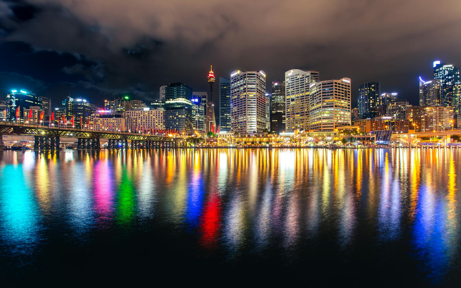 Stunning view of Sydney's skyline at night with colorful reflections in the water.