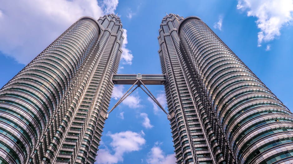 Low angle view of the iconic Petronas Twin Towers in Kuala Lumpur, Malaysia, against a clear blue sky.