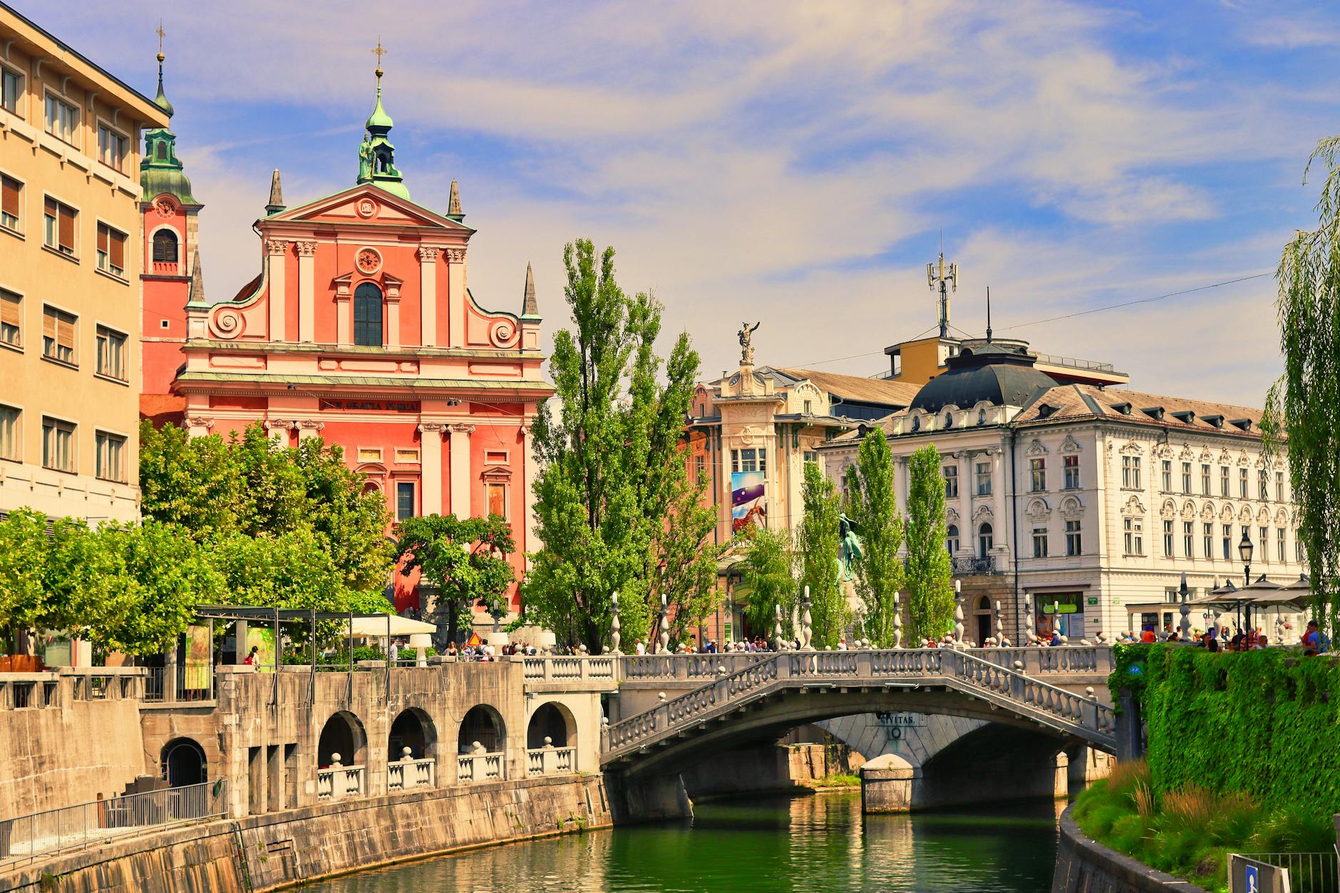Explore Ljubljana's vibrant cityscape with the Triple Bridge and Franciscan Church on a sunny day.