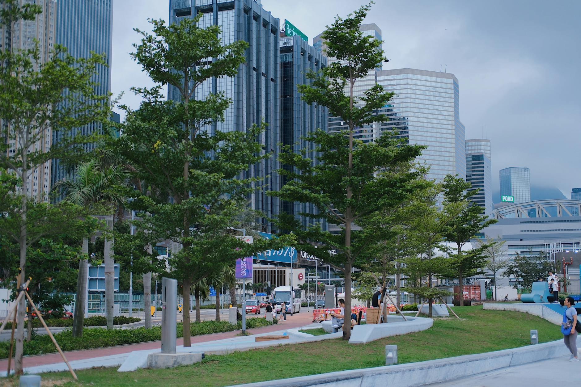 Vibrant Tamar Park with skyscrapers in downtown Hong Kong, featuring lush greenery and urban landscape.