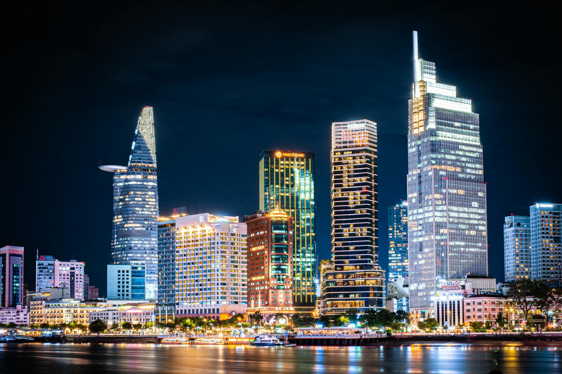 Stunning night view of Ho Chi Minh City's skyline with illuminated skyscrapers reflecting on the river.