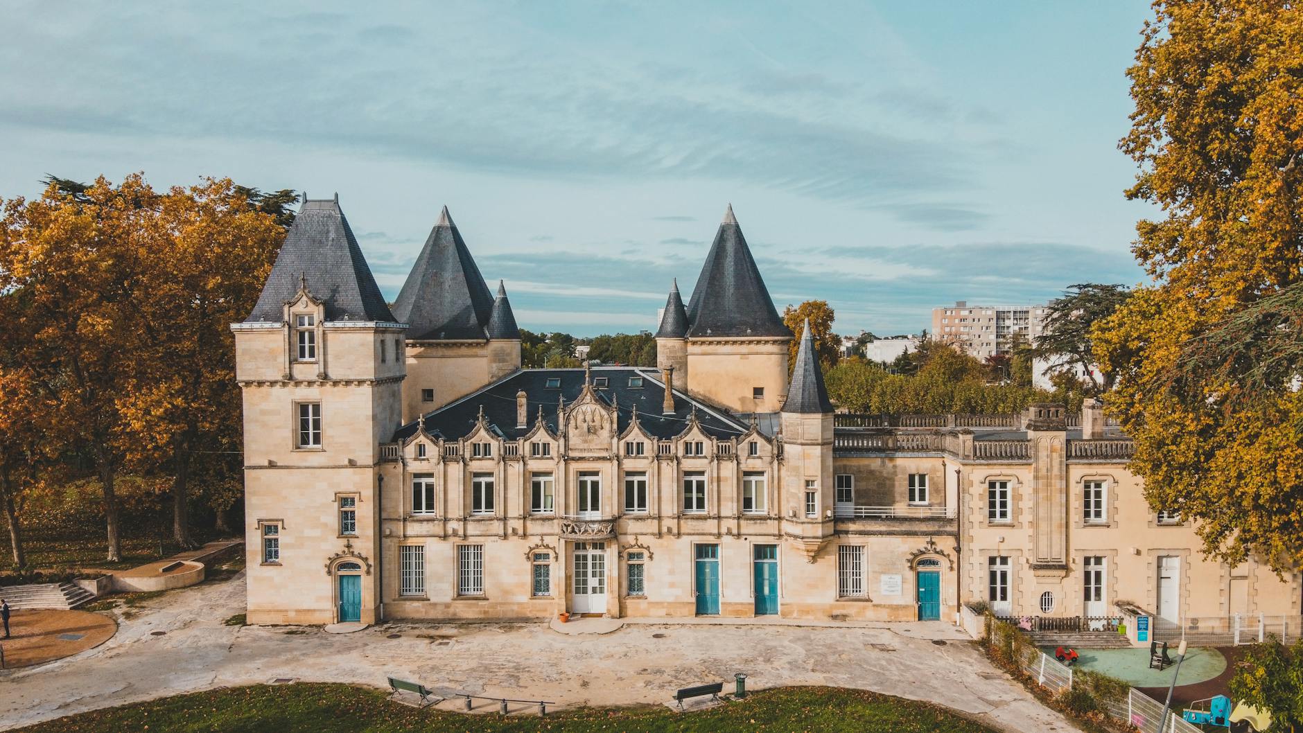 Majestic aerial shot of a historic château in Bordeaux surrounded by autumn trees.