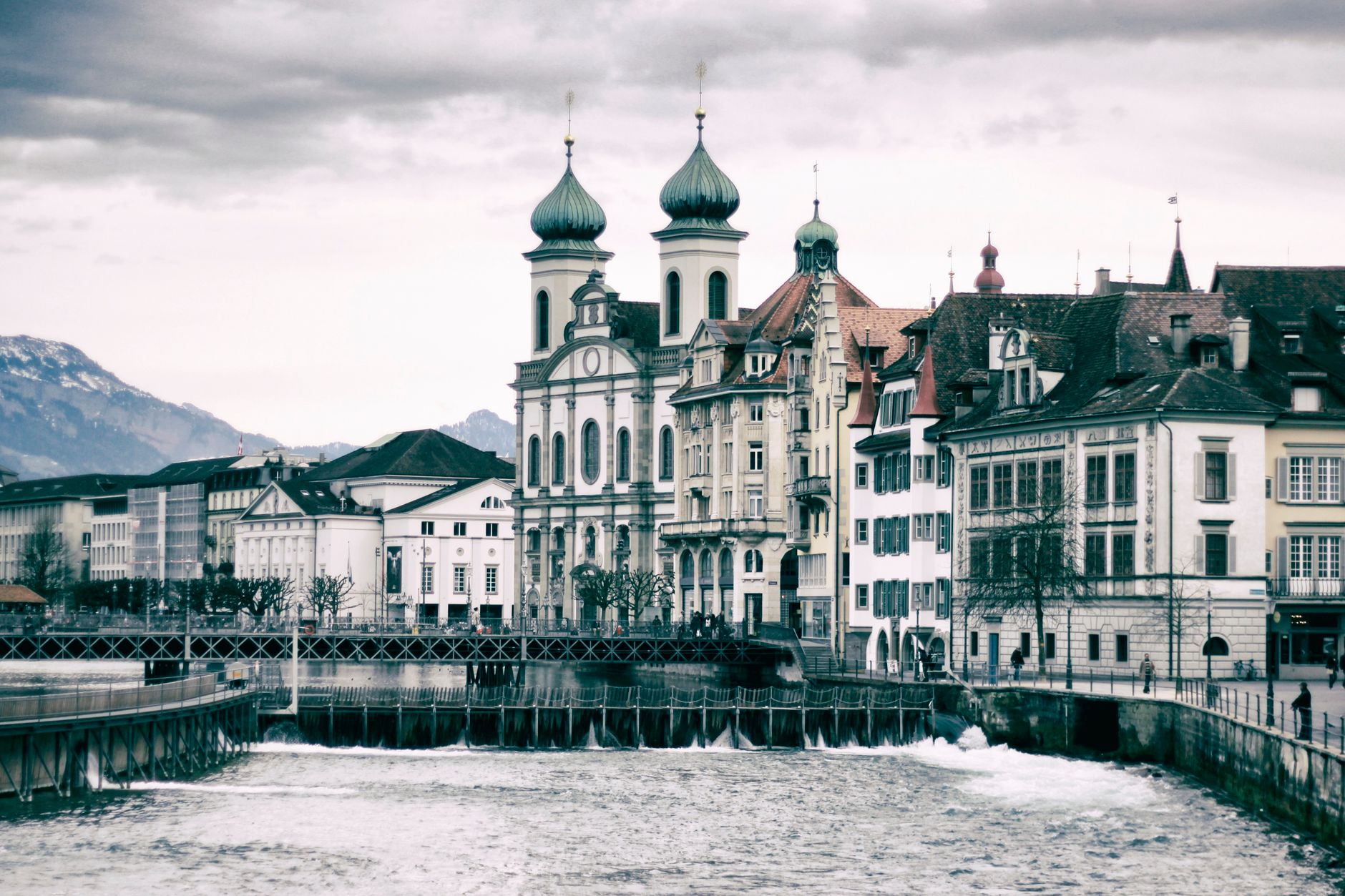 Picturesque view of Lucerne with iconic Jesuit Church and waterfront on a cloudy day.