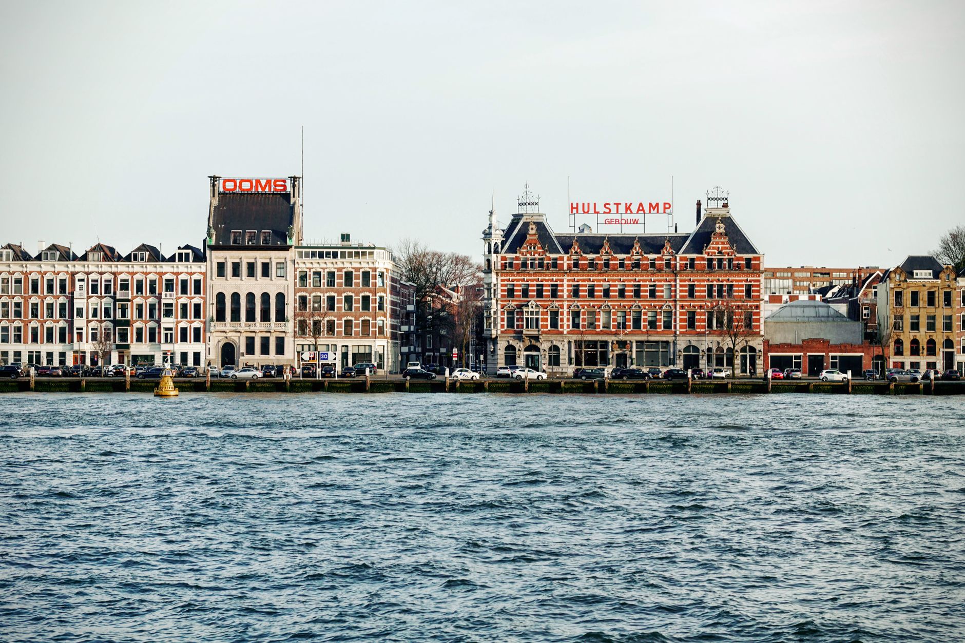 Beautiful view of historic facades along Rotterdam's vibrant waterfront on a clear day.