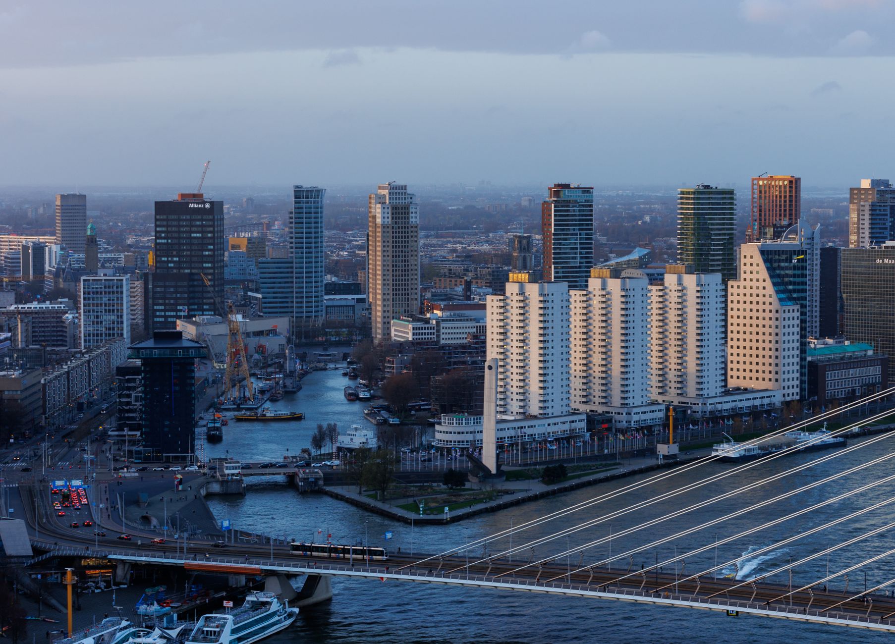 A breathtaking view of Rotterdam's modern skyline and Erasmus Bridge at dusk.