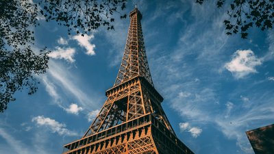 Stunning low-angle view of the Eiffel Tower against a vibrant blue sky with clouds in Paris.
