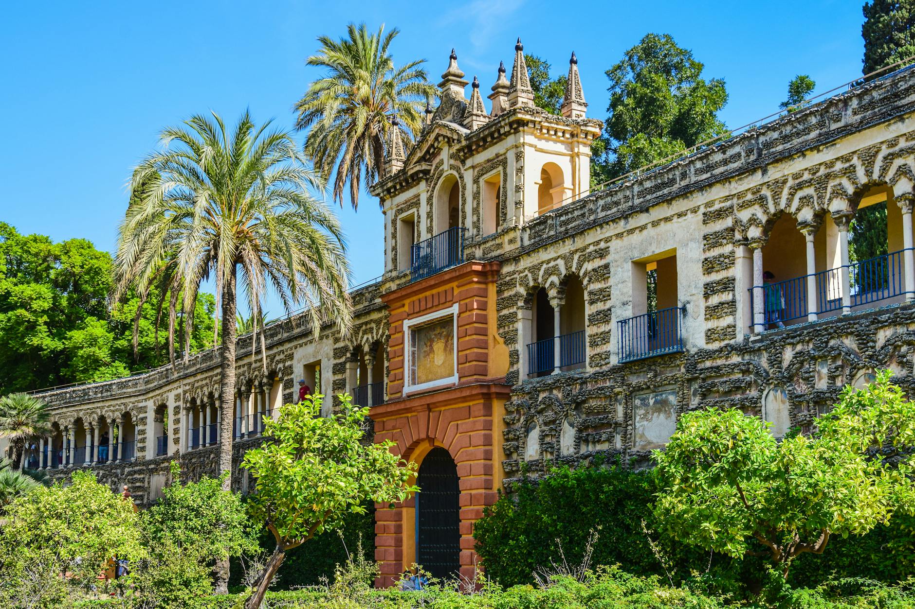 Discover the stunning Alcazar Palace with lush gardens, palm trees, and historic architecture in Seville, Spain.
