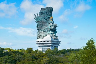 A majestic view of the Garuda Wisnu Kencana statue towering over lush landscapes in Bali, Indonesia.