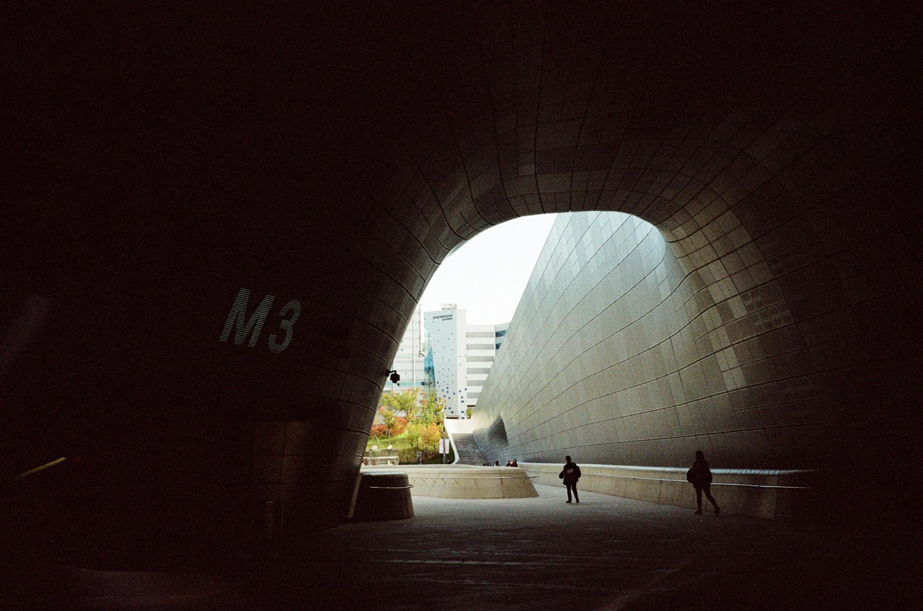 View of Dongdaemun Design Plaza's modern architecture with people in silhouette.
