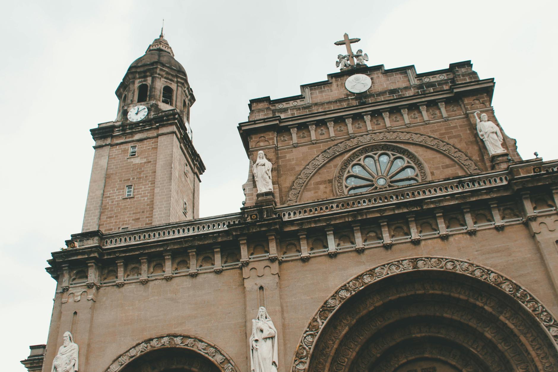 A dramatic view of the Manila Cathedral showcasing its neo-romanesque architecture with statues and clock tower.