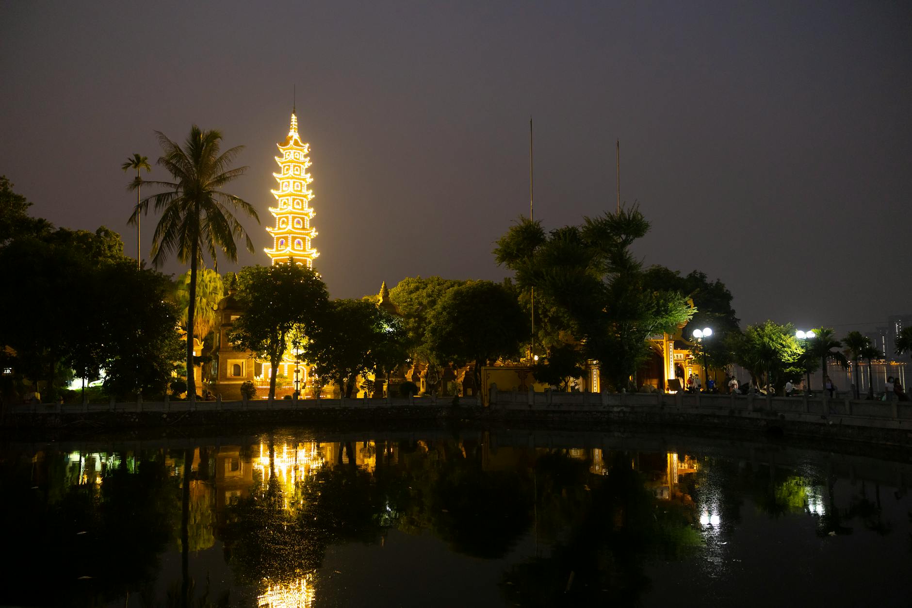 Scenic view of a beautifully lit pagoda reflecting in a pond at night.