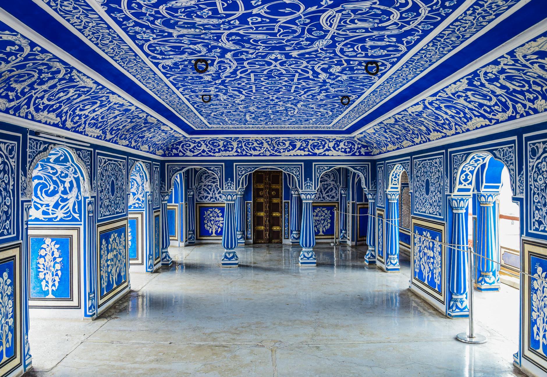 Intricately decorated blue interior of a historic city palace, showcasing vibrant murals and ornate architecture.
