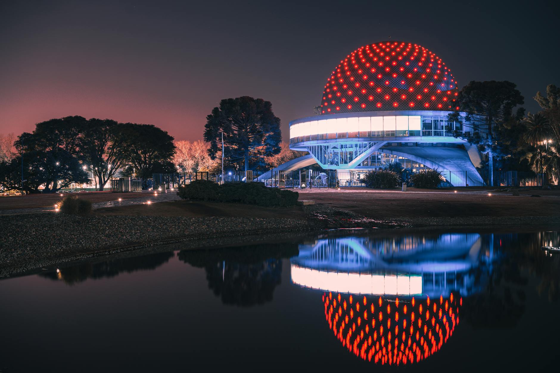 Illuminated Buenos Aires planetarium reflected in water at night.