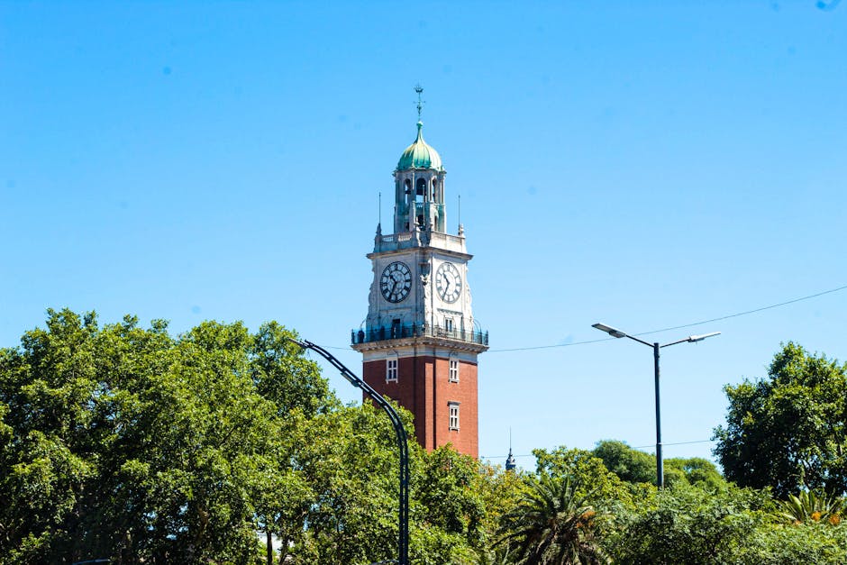 Clock Tower surrounded by trees in Buenos Aires, Argentina, under a clear blue sky.