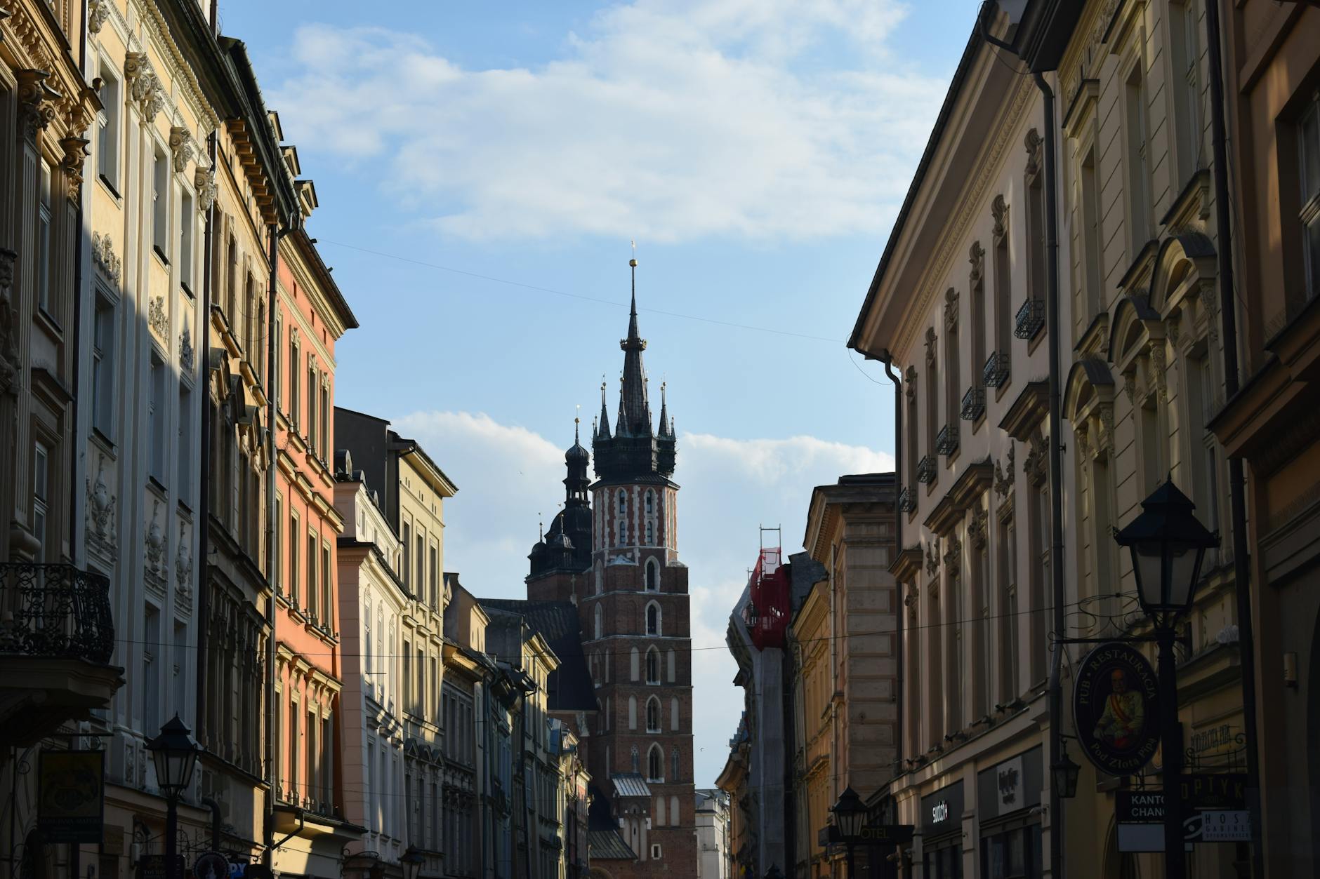 Charming Krakow street with St. Mary's Basilica, capturing historic architecture under a bright sky.