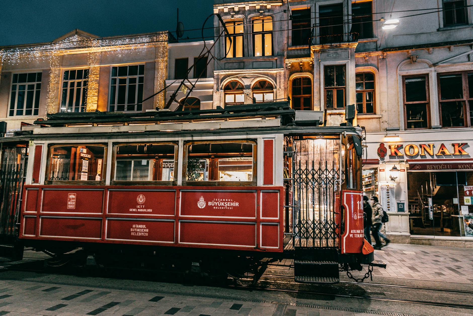 Old fashioned tramway riding on rails along paved street with buildings in city
