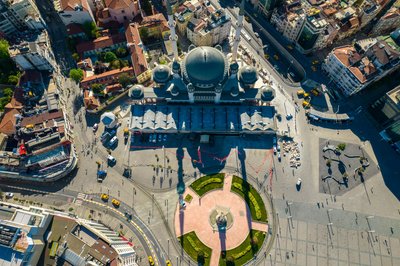 Aerial shot of a prominent mosque amidst a busy city, showcasing vibrant architecture and urban life.
