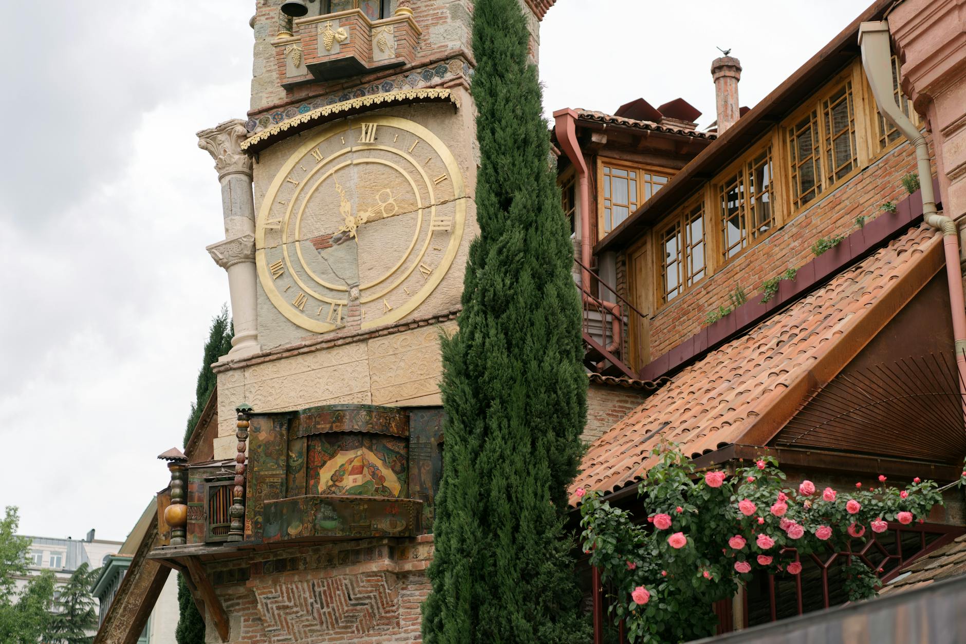 A picturesque vintage clock tower with a rustic facade surrounded by greenery and flowers.