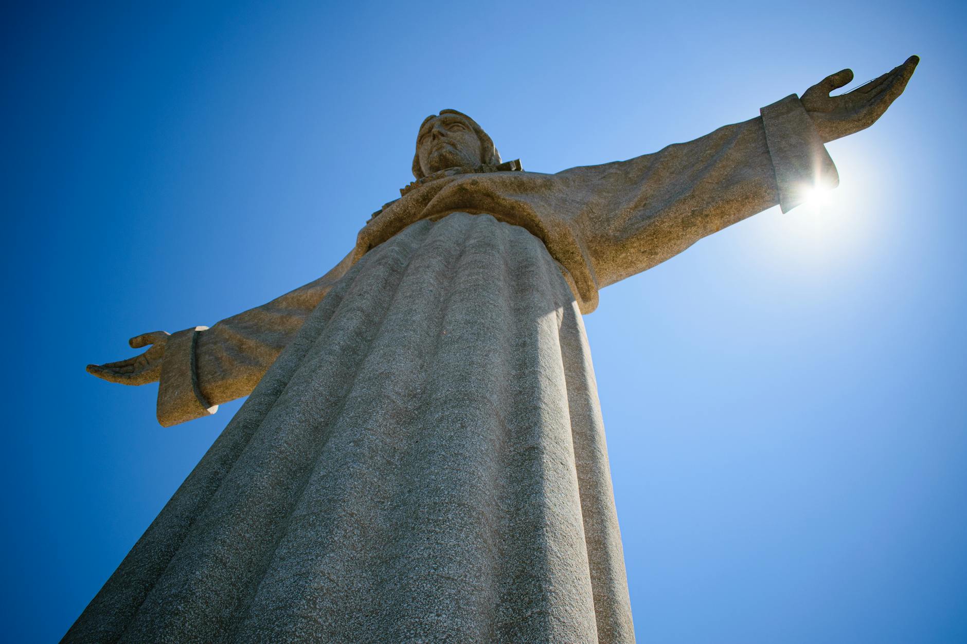 View of the iconic Cristo Rei statue in Almada, Portugal against a clear blue sky.