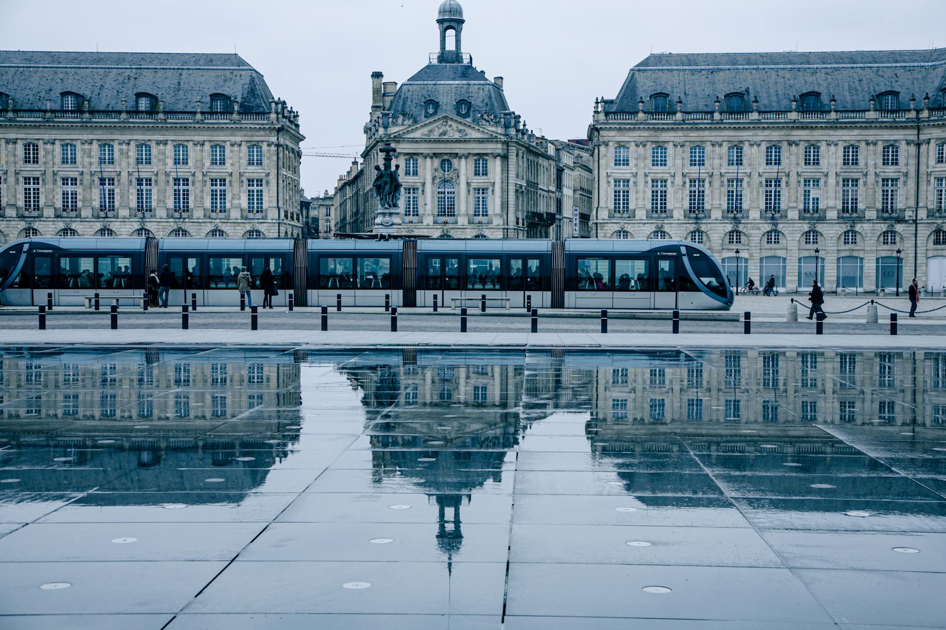 Tram passing by the historic Place de la Bourse in Bordeaux, reflecting on the Miroir d'eau.