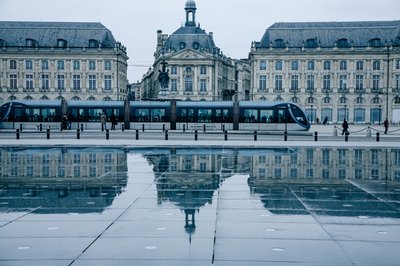 Tram passing by the historic Place de la Bourse in Bordeaux, reflecting on the Miroir d'eau.