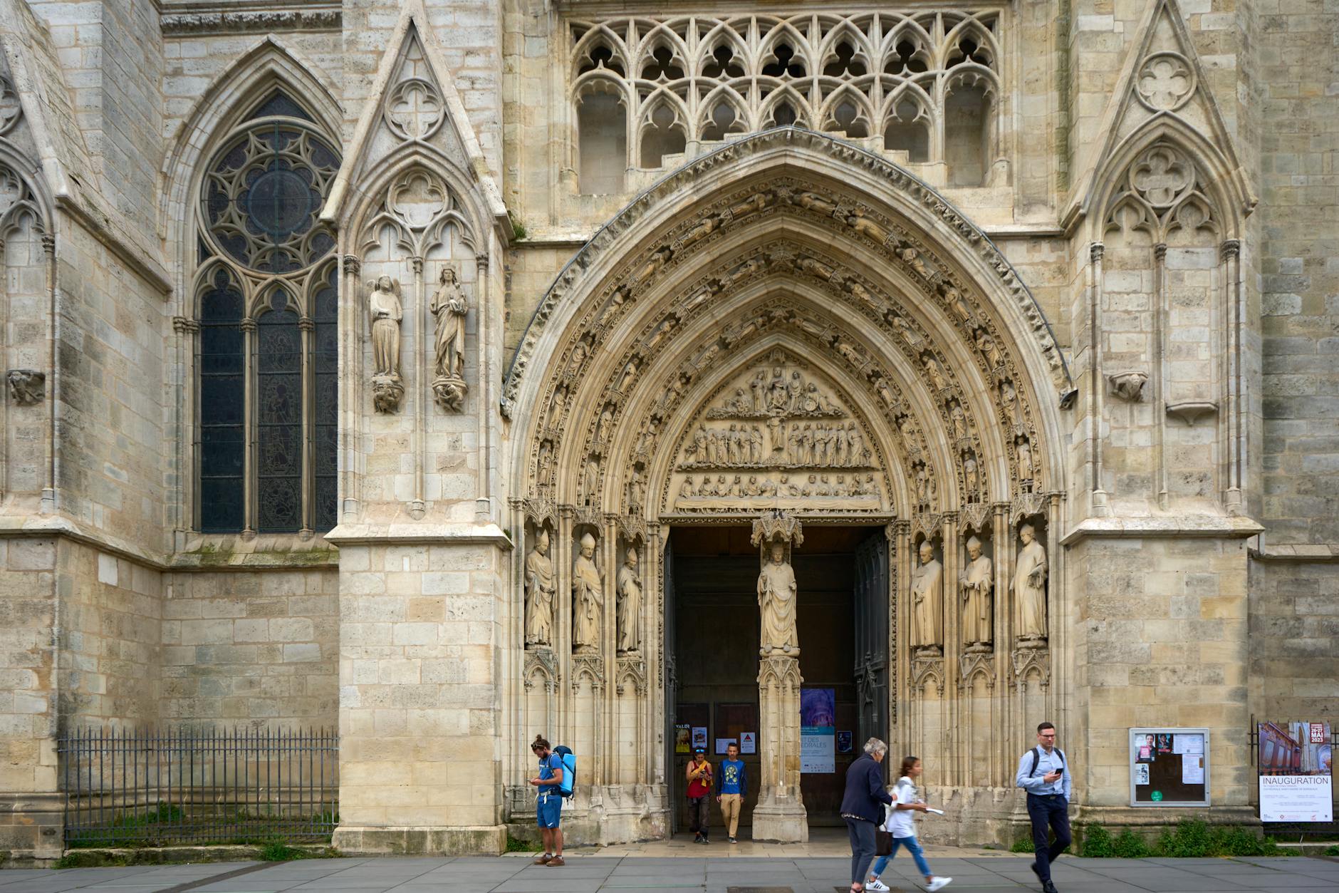 Intricate Gothic architecture of Bordeaux Cathedral with people at the entrance in Bordeaux, France.