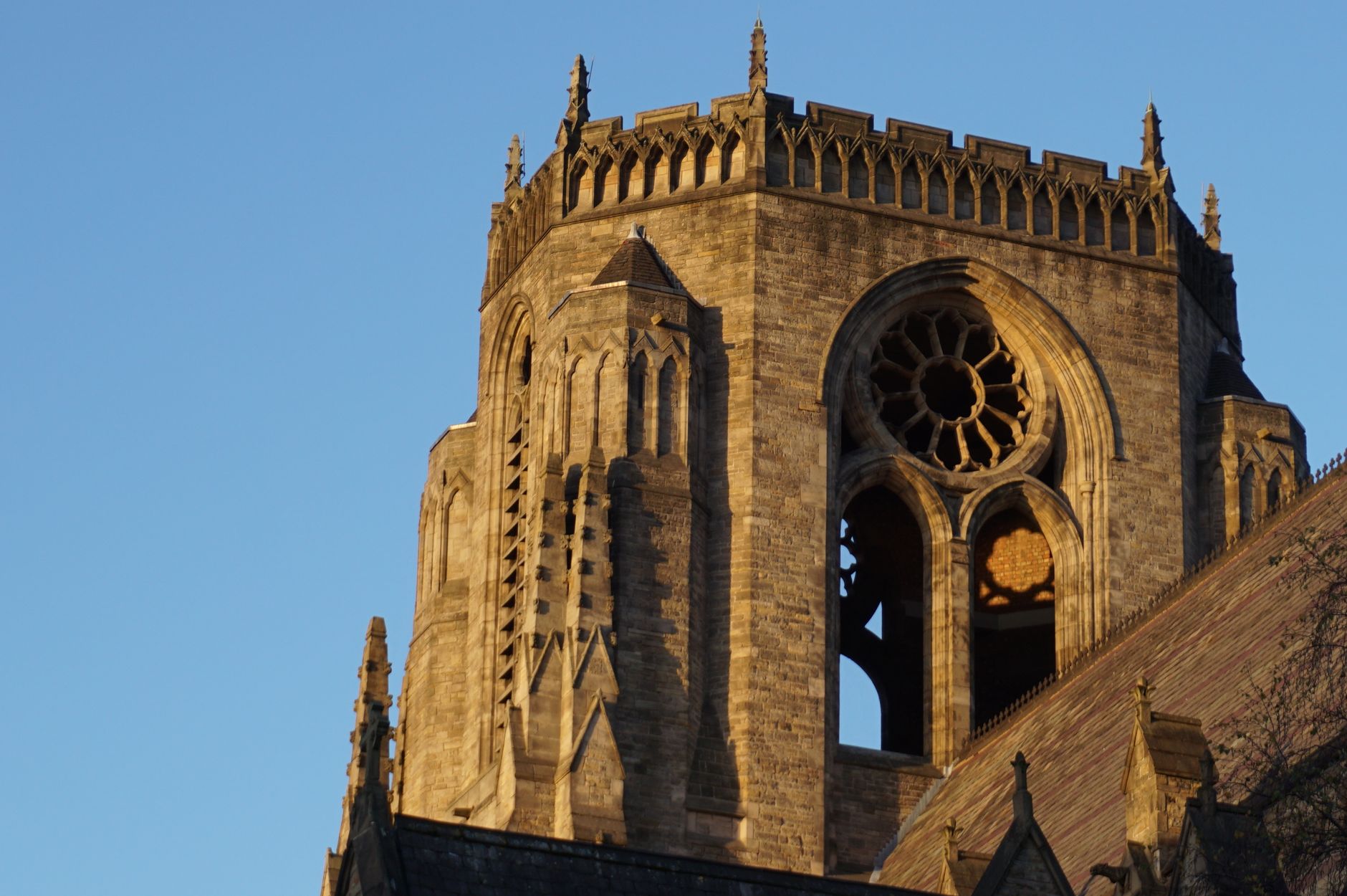 Close-up view of a Gothic cathedral tower in Manchester, England during sunset.