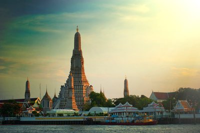 Stunning sunset view of Wat Arun temple by the Chao Phraya River in Bangkok, Thailand.