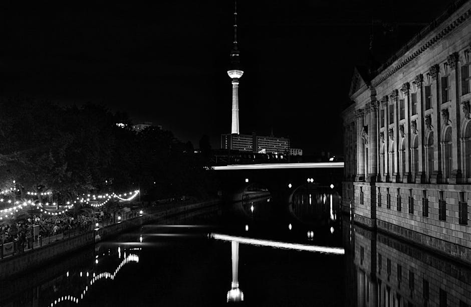 Black and white night scene of Berlin TV Tower reflected over the water.