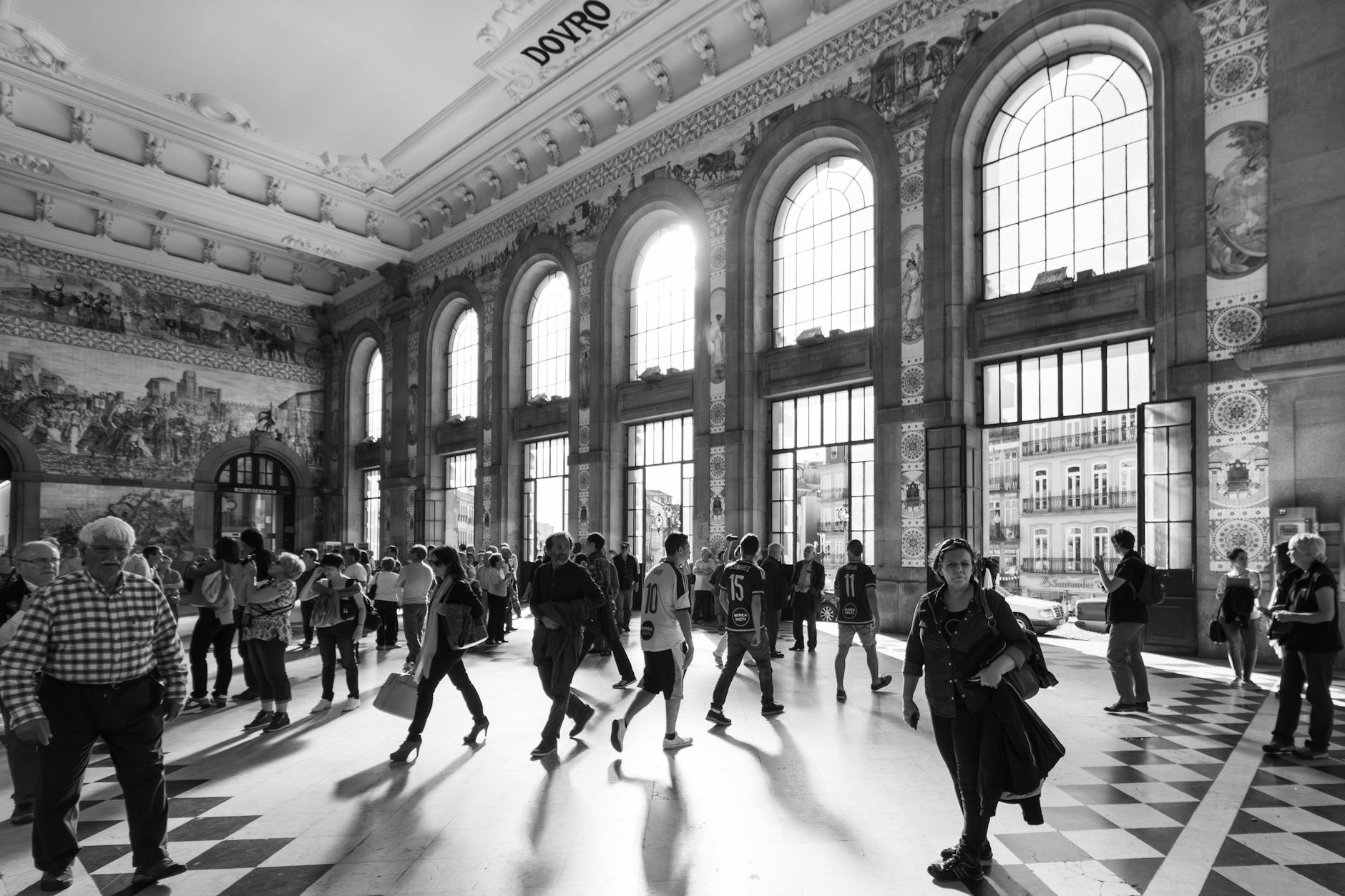 Historic São Bento Railway Station interior with people walking past the large windows.