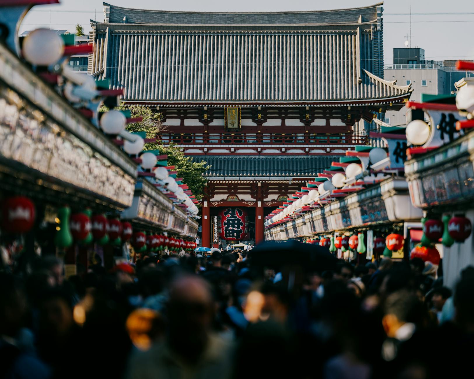 Busy street leading to Senso-ji Temple in Tokyo, capturing a bustling crowd and colorful architecture.