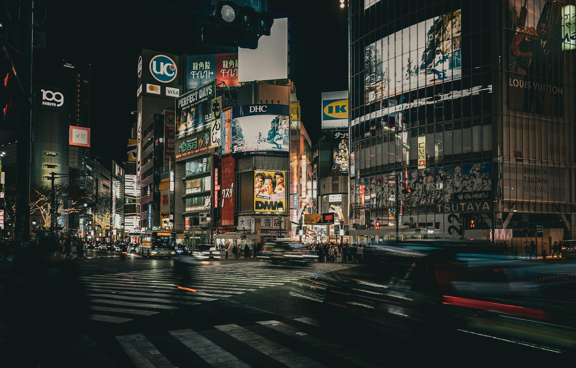 Bustling night scene at Shibuya crossing in Tokyo with vibrant advertisements and bustling traffic.