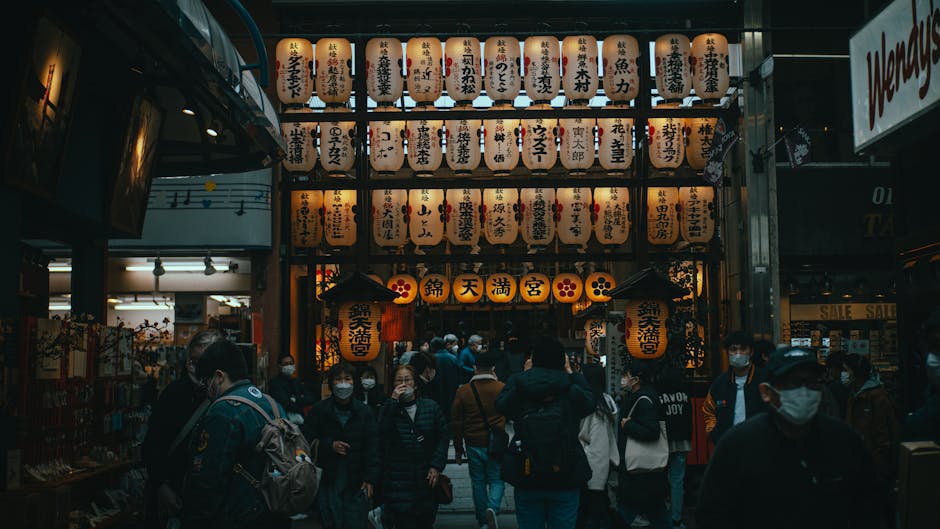 Crowd at Nishiki Tenmangu Shrine, Kyoto with illuminated lanterns creating a vibrant urban scene.