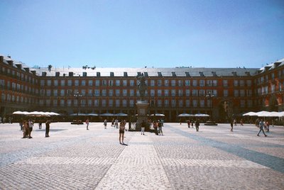 View of Plaza Mayor in Madrid with historical architecture, cobblestones, and tourists.