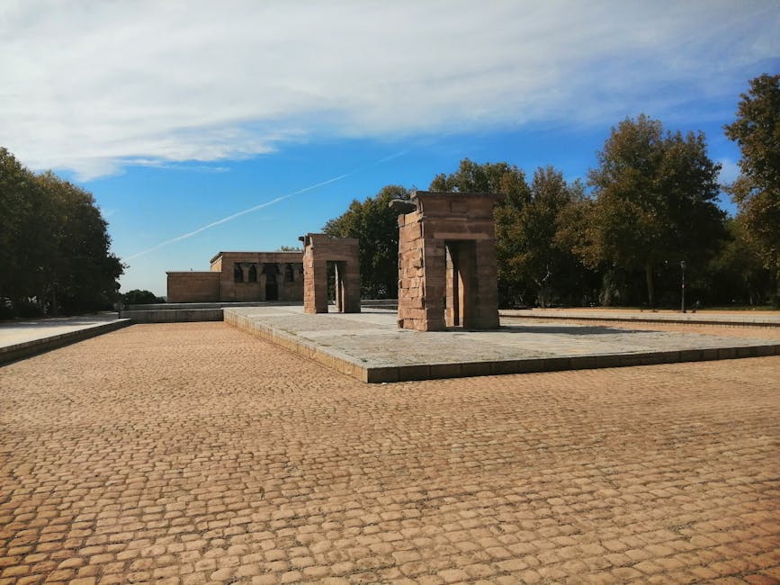 The ancient Temple of Debod in Madrid surrounded by trees under a blue sky.