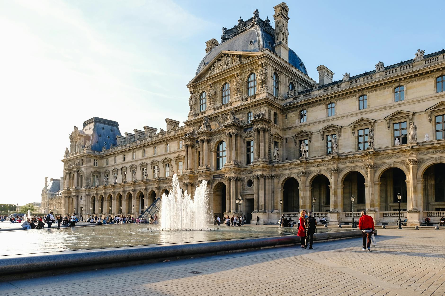 View of the Louvre Museum with a fountain in the courtyard, a popular tourist spot in Paris.