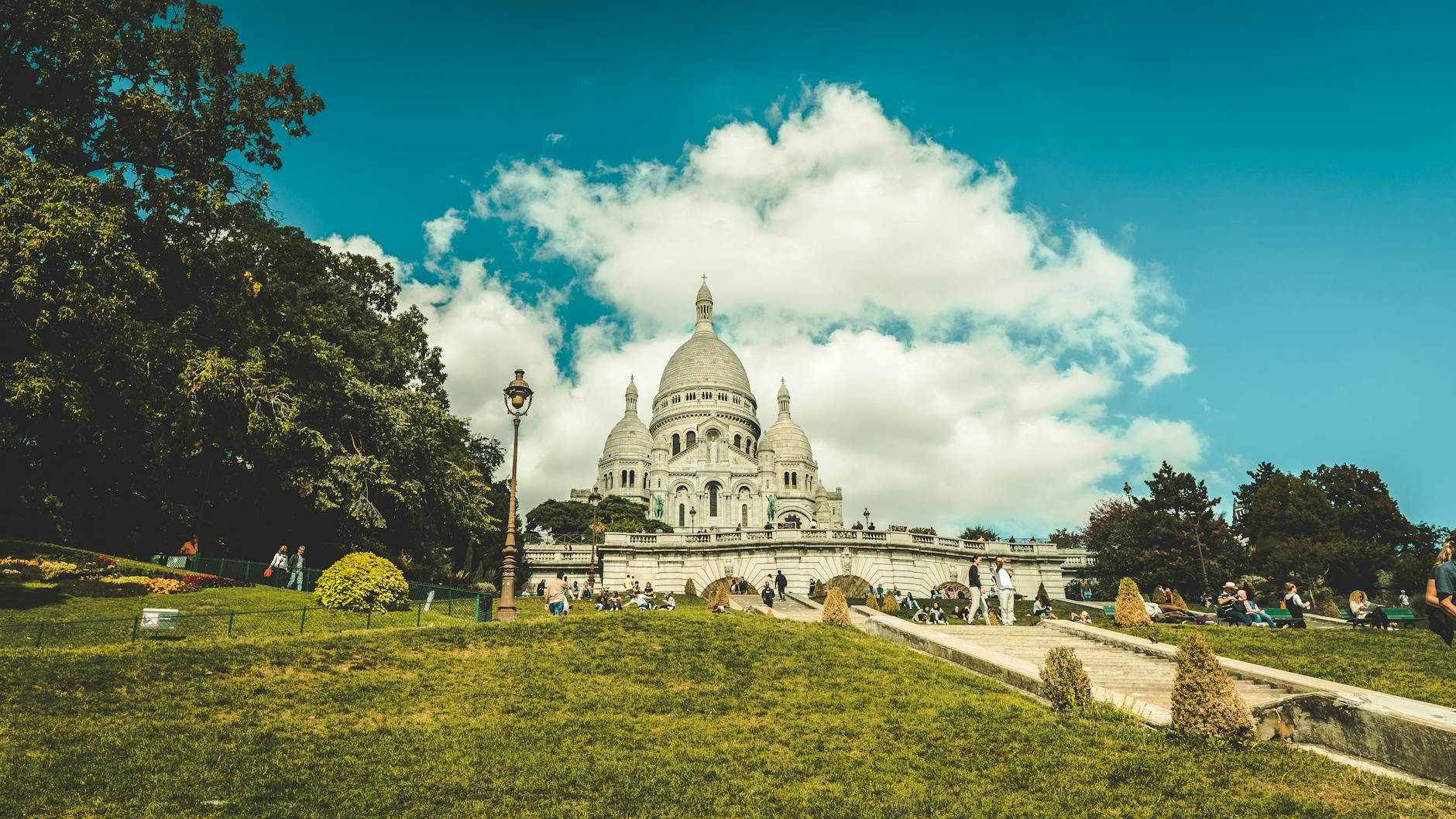 Stunning view of Sacre-Coeur Basilica with people enjoying the park on a sunny day.