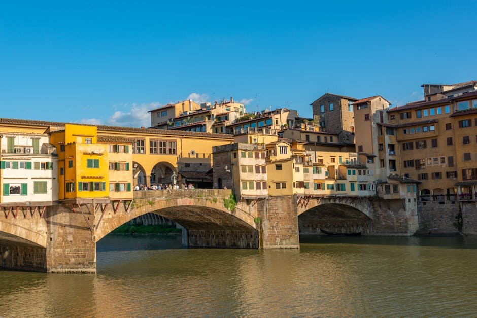 View of the historic Ponte Vecchio bridge over the Arno River in Florence, Italy during a sunny day.