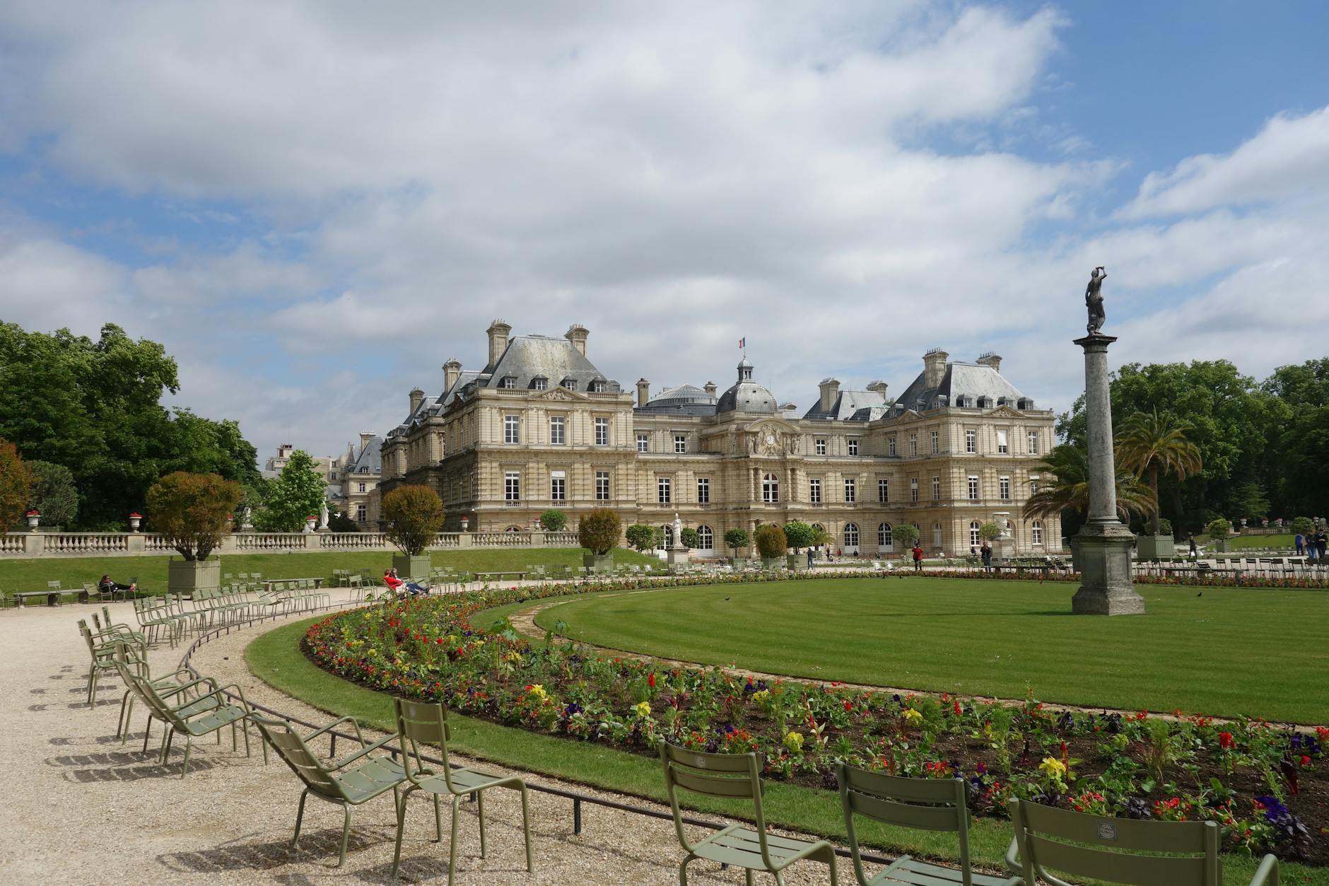 Luxembourg Palace and its gardens in Paris under a bright blue sky, showcasing architecture and nature.