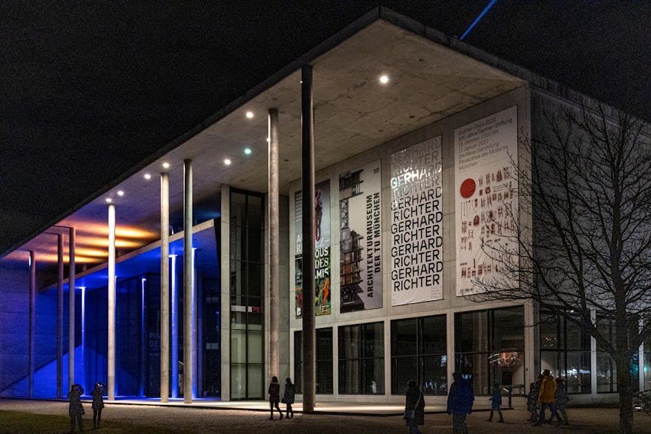 Night view of Pinakothek der Moderne in Munich with colorful lighting and visitors.
