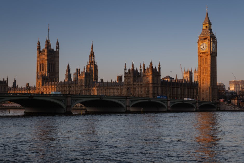 Stunning view of Big Ben and the Houses of Parliament at sunset in London, England, with reflections on the Thames River.