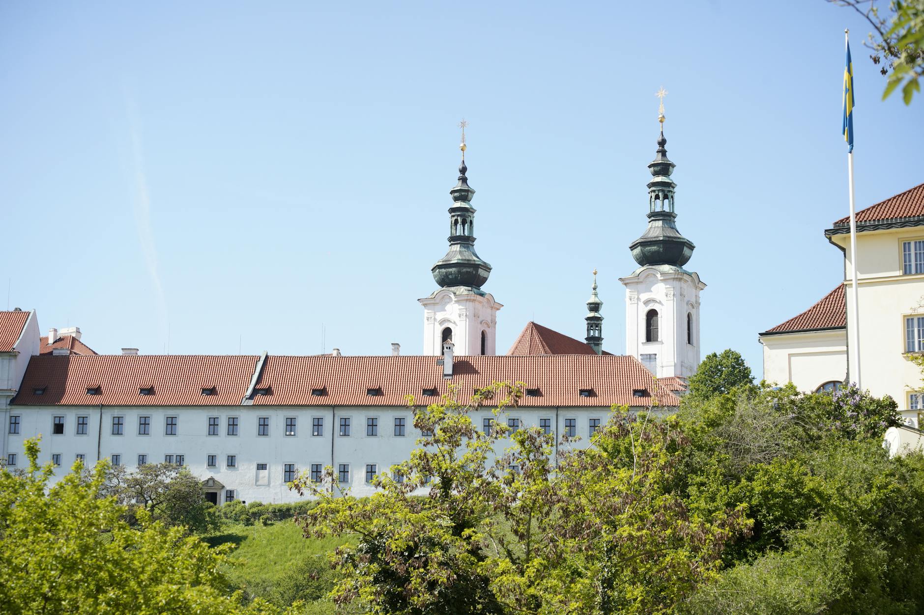 View of historic monastery with spires under clear blue sky in Prague, Czech Republic.