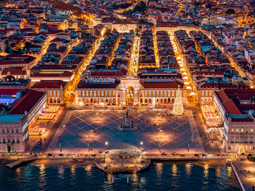 Stunning aerial view of Lisbon's Praça do Comércio at dusk with vibrant city lights and illuminated streets.