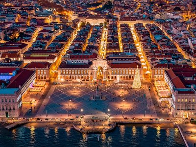 Stunning aerial view of Lisbon's Praça do Comércio at dusk with vibrant city lights and illuminated streets.