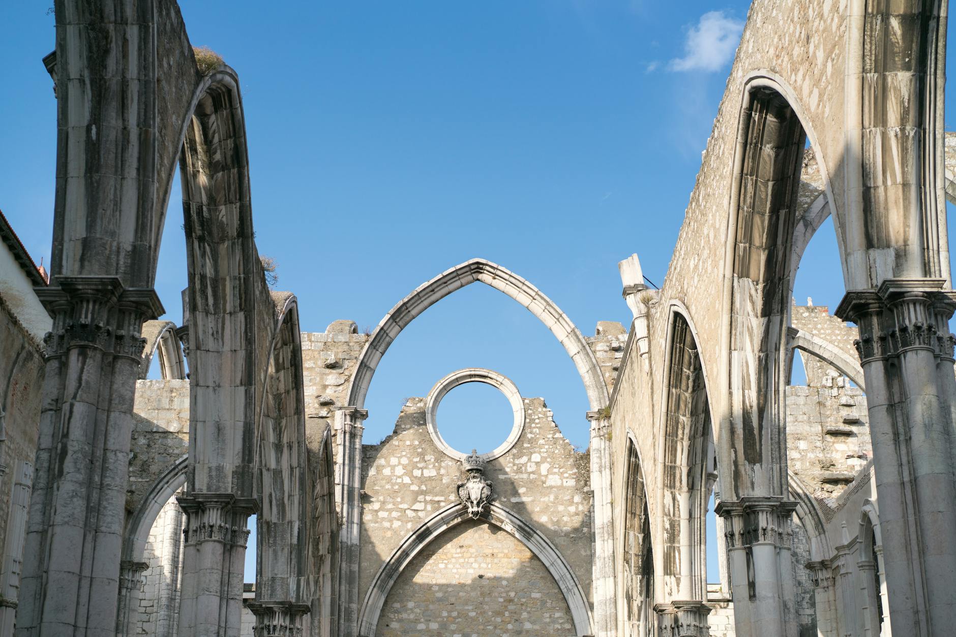 Explore the historic Carmo Convent ruins in Lisbon, showcasing stunning Gothic architecture under a clear blue sky.