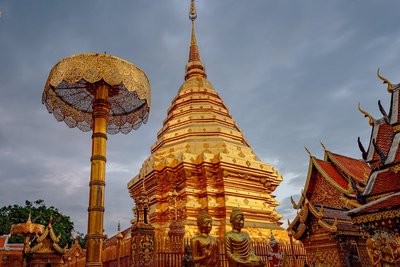 Stunning view of the golden Wat Phra That Doi Suthep pagoda under cloudy skies in Chiang Mai, Thailand.