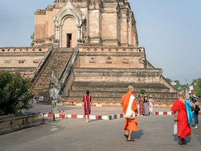 Monks and tourists at Wat Chedi Luang, a historic temple in Chiang Mai, Thailand.