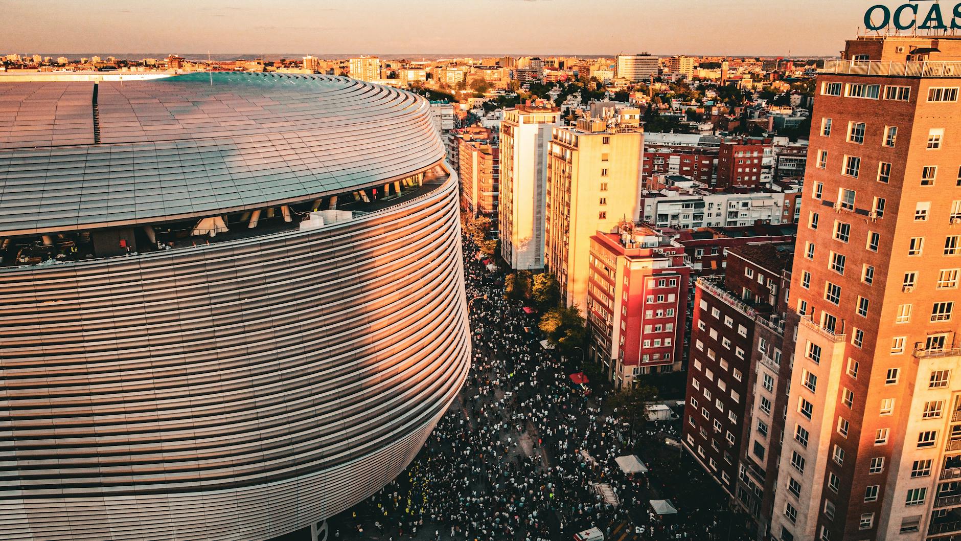 Aerial view of a stadium and bustling cityscape in Madrid, Spain during sunset.